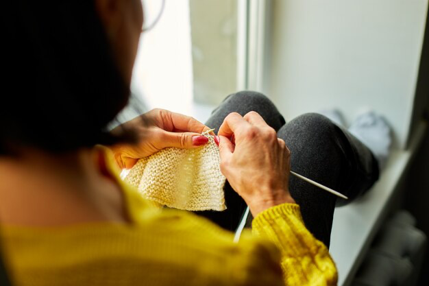 Woman sitting on the windowsill and knitting