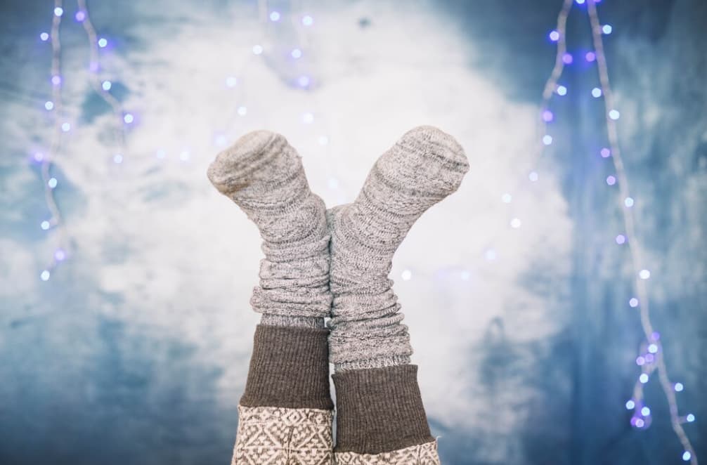 legs dressed in gray knitted socks in front of the blue marble wall with blue lights behind