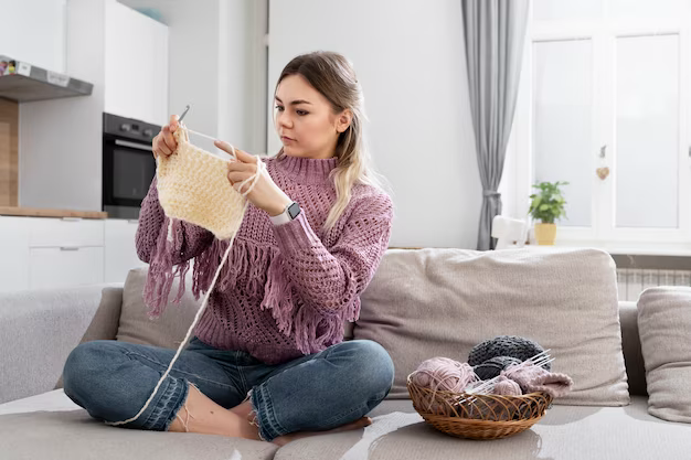 Girl knits while sitting on the sofa