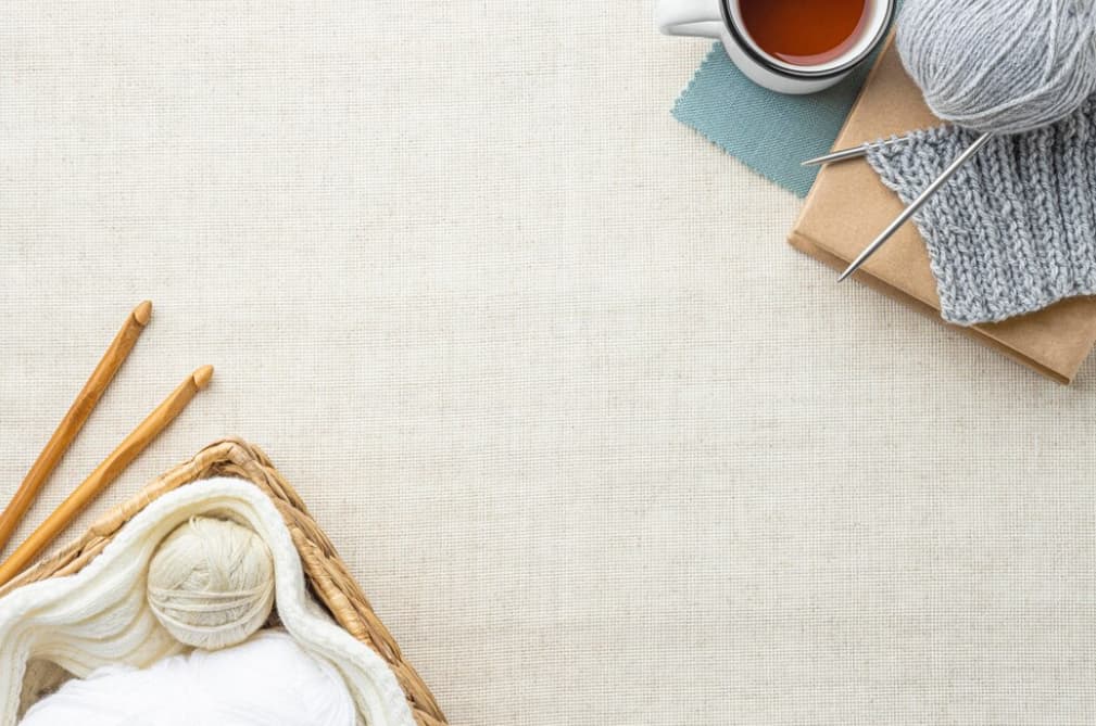 A cozy knitting setup with yarn, needles, and tea on a canvas background