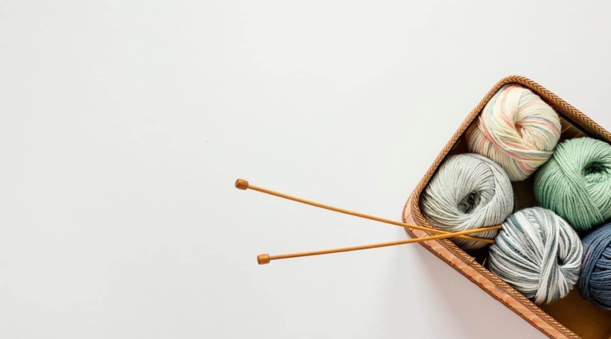 colorful yarns with needles in the basket on a white background