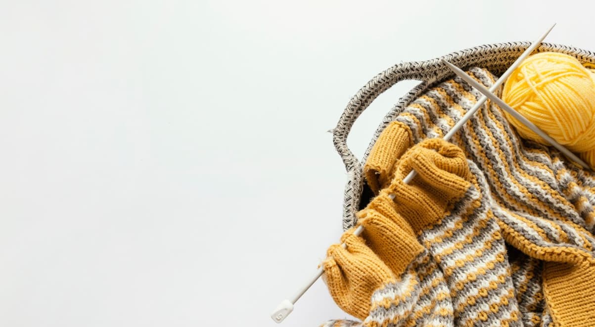 Knitting needles and wool in a basket on white background